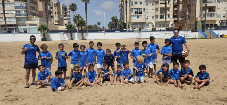 Grupo de niños en la playa con camisetas azules de fútbol