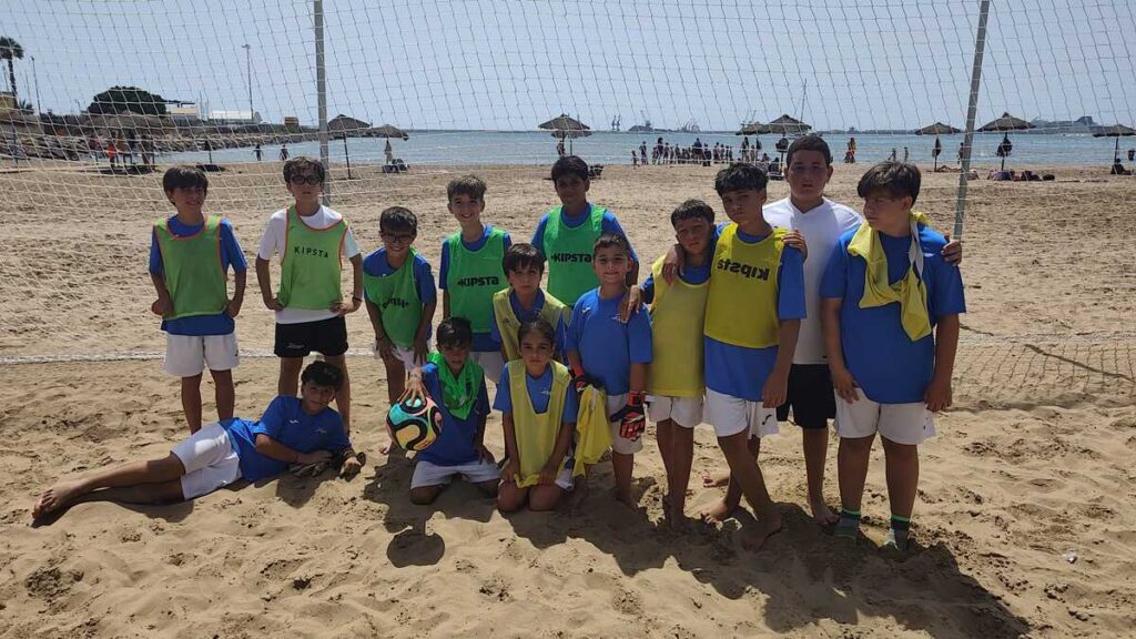 Grupo de niños jugando al fútbol en la playa