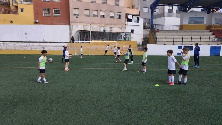 Youth soccer practice on a turf field with cones and kids in white and green pinnies waiting for drills
