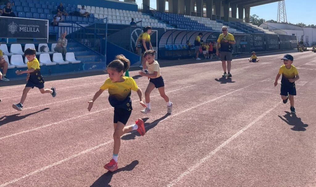Niños corriendo en una pista de atletismo durante un torneo escolar.