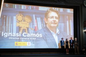Ignasi Camós en un evento con proyector y libros de fondo