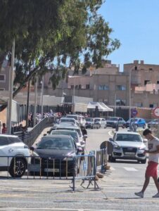 Colas de vehículos en la frontera de Melilla con personas esperando.