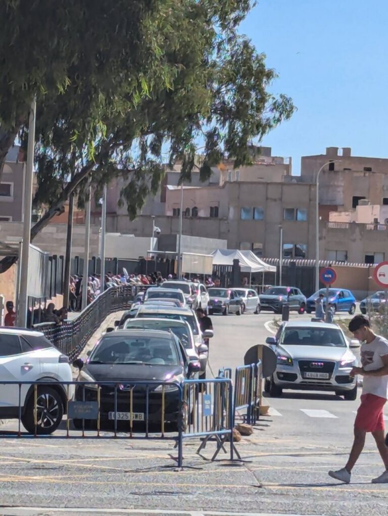 Colas de vehículos en la frontera de Melilla con personas esperando.