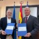 Dos hombres sosteniendo documentos en un acto de firma de convenio