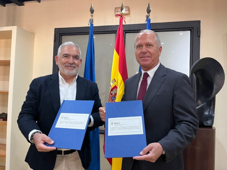 Dos hombres sosteniendo documentos en un acto de firma de convenio
