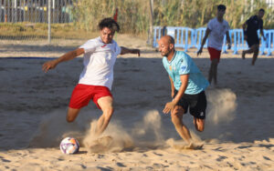 Jugadores de fútbol playa compitiendo en la arena durante un partido.