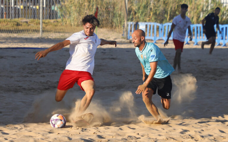 Jugadores de fútbol playa compitiendo en la arena durante un partido.
