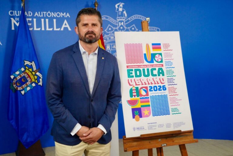 Public official standing beside a colorful poster for 'Educa Verano 2026' in a blue Melilla backdrop event room.