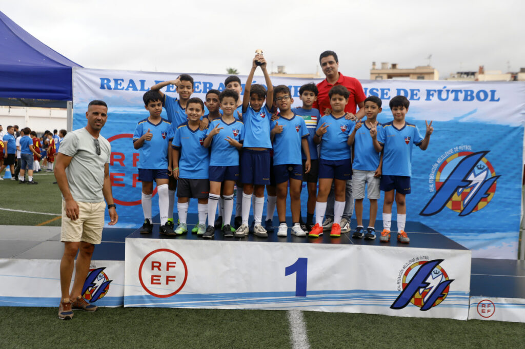 Grupo de niños con trofeo en evento de fútbol infantil