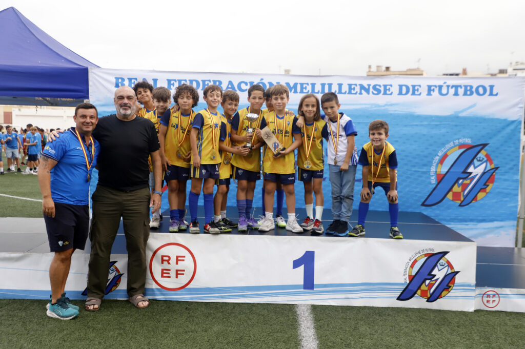 Equipo de fútbol juvenil con medallas y trofeo en Melilla