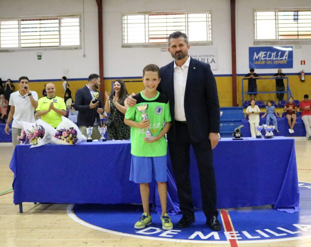 Niño sonriente recibiendo un trofeo en la entrega de premios de balonmano
