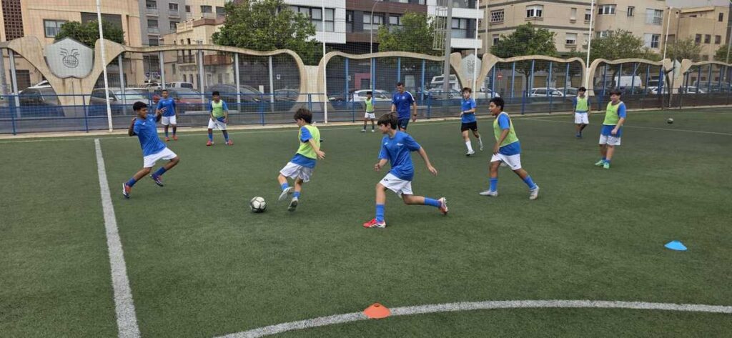 Grupo de jóvenes entrenando fútbol en un campo verde