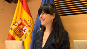 Mujer sonriendo en un evento con banderas de España y Europa