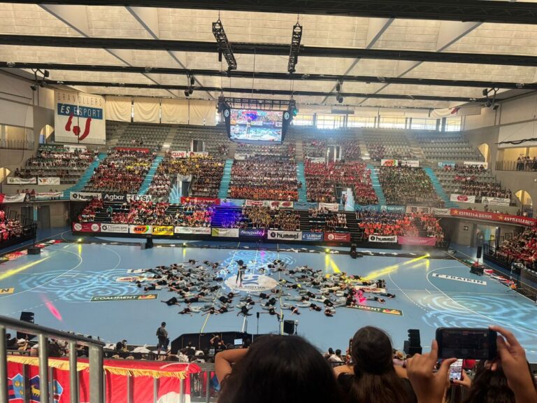 Vista del pabellón lleno durante un evento deportivo con actuaciones en el suelo.