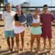 Cuatro jugadores sosteniendo palas de pádel en la playa