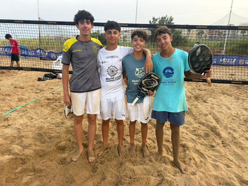 Cuatro jóvenes jugadores de tenis playa posando en la arena