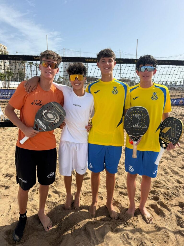 Cuatro jóvenes jugadores de tenis playa posando en la arena