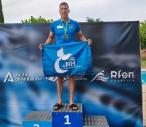 Jesús Herrero en el podio con medalla de oro y bandera del Club Natación Melilla