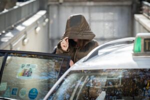 Persona con capucha saliendo de un taxi en un contexto judicial