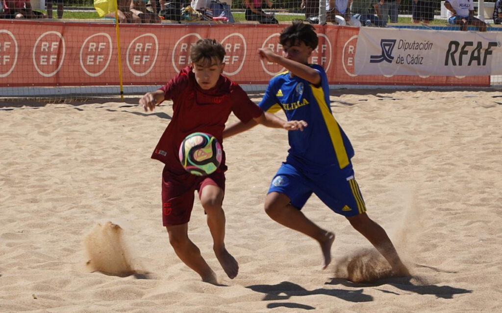 Niños jugando al fútbol playa en un partido de competición