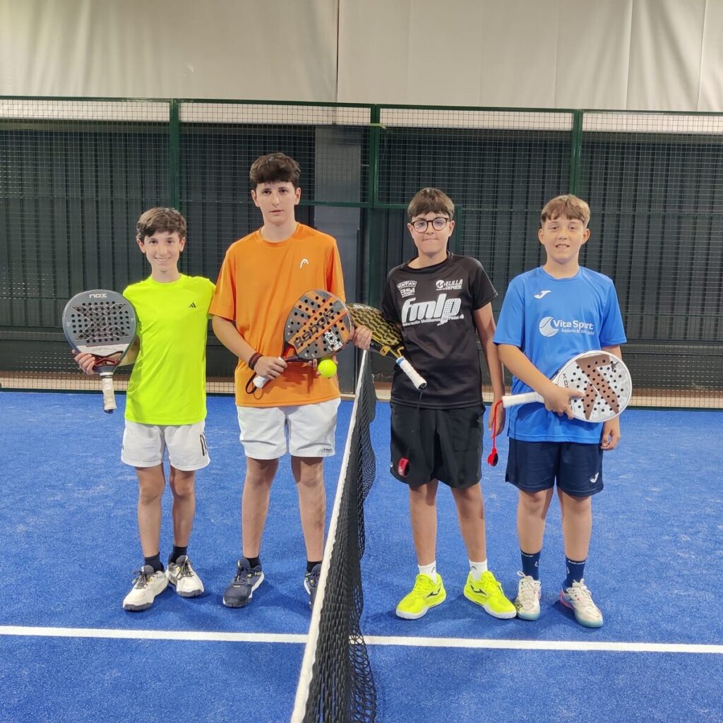 Cuatro jóvenes jugadores de pádel posando en una cancha
