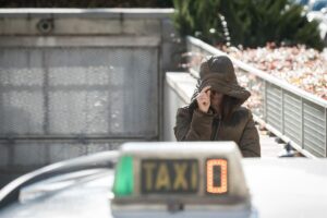 Leire Díez con capucha en la calle cerca de un taxi