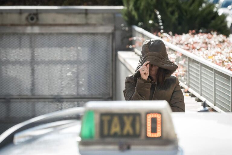 Leire Díez con capucha en la calle cerca de un taxi