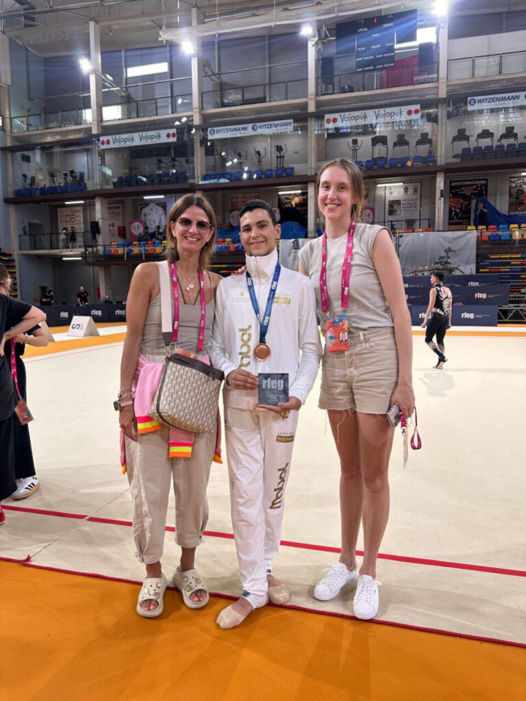 Leo Faus con medalla de bronce rodeado de dos mujeres en el campeonato de gimnasia.