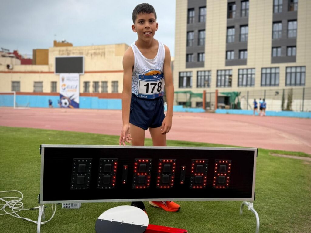 Joven atleta Nizar Benali mostrando su tiempo en una competición de medio fondo.