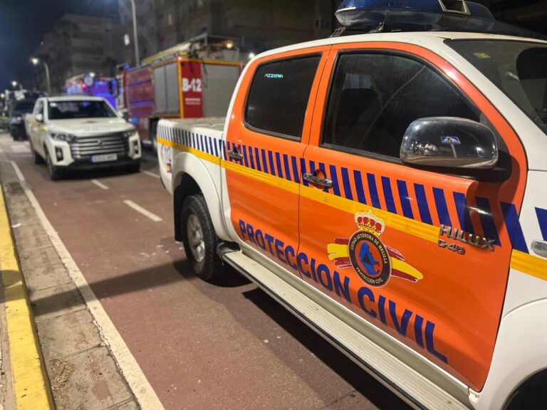 Emergency civil protection vehicle parked on a city street at night, orange and white with blue stripes and crest reading 'Protección Civil'