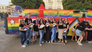 Grupo de personas celebrando el Día Internacional del Orgullo LGTBI con banderas de colores.