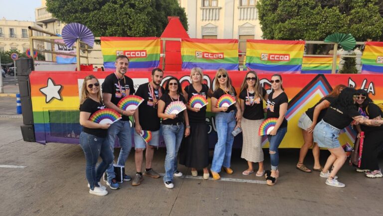 Grupo de personas celebrando el Día Internacional del Orgullo LGTBI con banderas de colores.