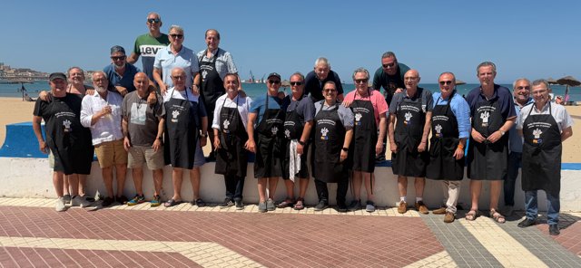 Grupo de personas en la playa con delantales en evento gastronómico