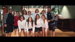 Group of young athletes posing for a team photo indoors, all in white hoodies with two coaches on the sides designer casual workout wear.