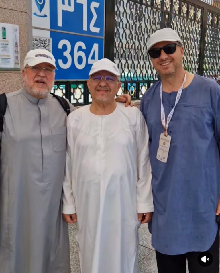 Tres peregrinos melillenses posando en La Meca con vestimenta tradicional.