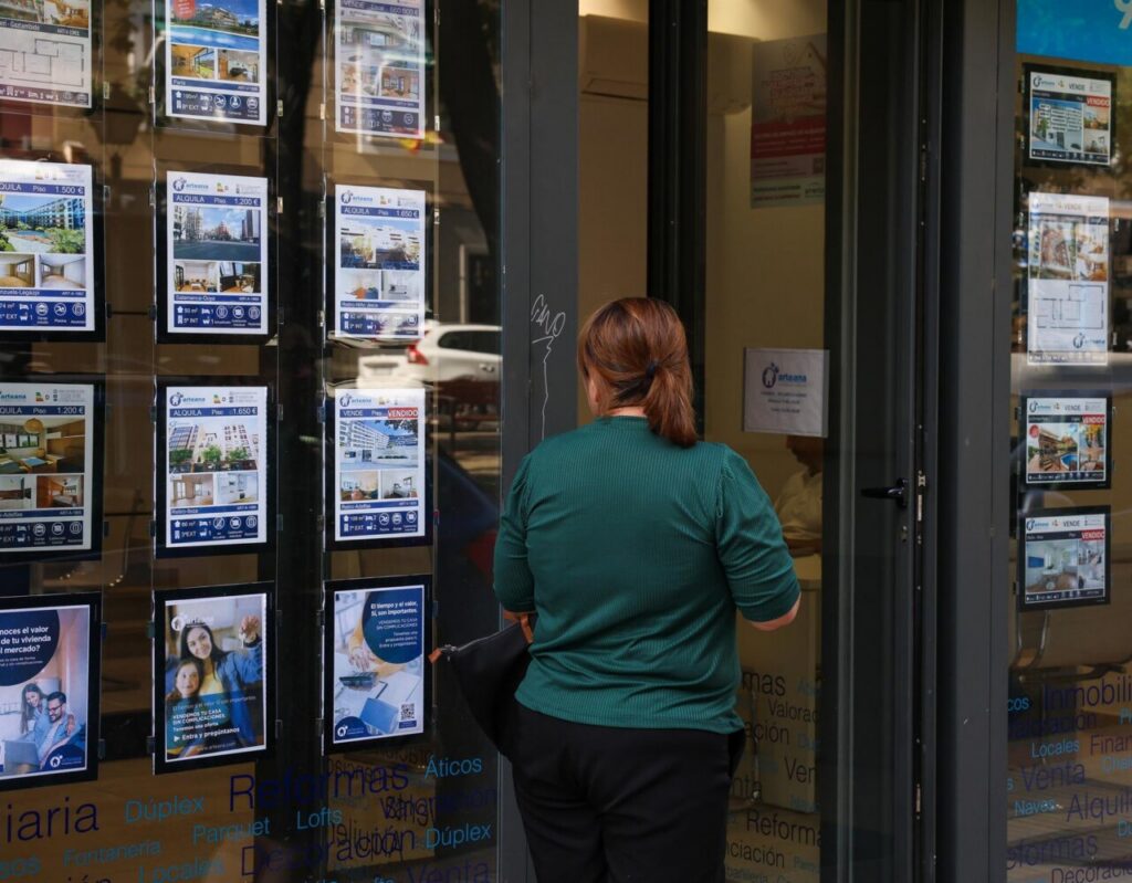 Persona observando anuncios de venta y alquiler de viviendas en una inmobiliaria