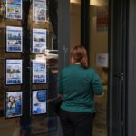 Persona observando anuncios de venta y alquiler de viviendas en una inmobiliaria