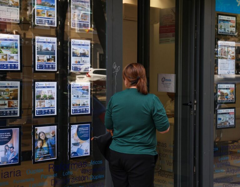 Persona observando anuncios de venta y alquiler de viviendas en una inmobiliaria