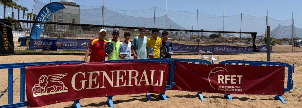 Group of seven players posing behind a red barrier on a sandy beach tennis court, with GENERALI and RFET banners in the foreground