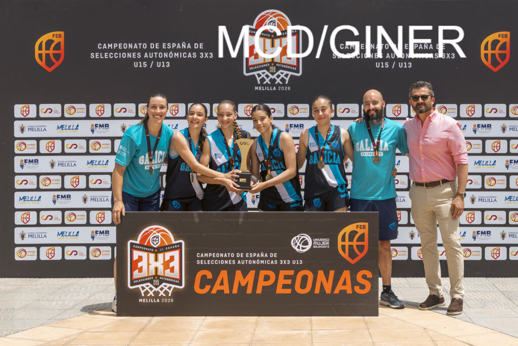 Girls basketball team in teal and black uniforms pose with trophy on a winners' stage, flanked by coaches, with a 'CAMPEONAS' backdrop behind them.