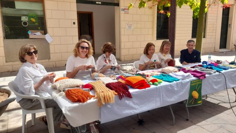 Grupo de mujeres tejiendo ovillos en una mesa al aire libre