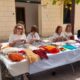 Grupo de mujeres tejiendo ovillos en una mesa al aire libre
