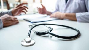 Consulta médica con un estetoscopio en la mesa y manos gesticulando