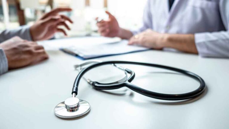 Consulta médica con un estetoscopio en la mesa y manos gesticulando