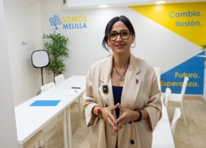 Mujer con abrigo claro en oficina de Somos Melilla
