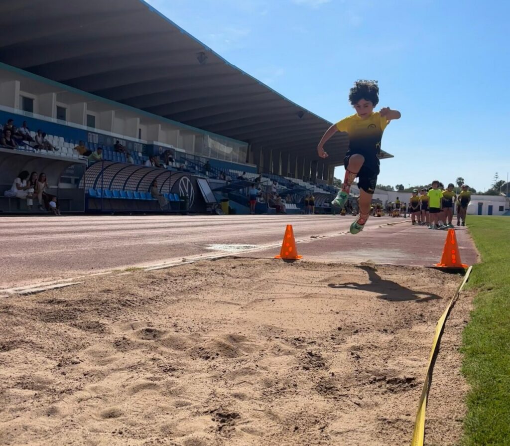 Niño saltando en la prueba de salto de longitud durante el torneo de atletismo
