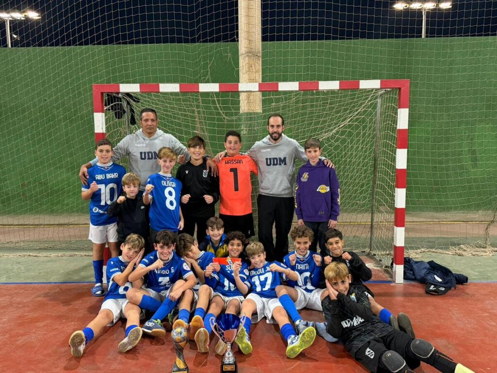 Equipo alevín de fútbol sala de la U.D. Melilla posando con trofeo