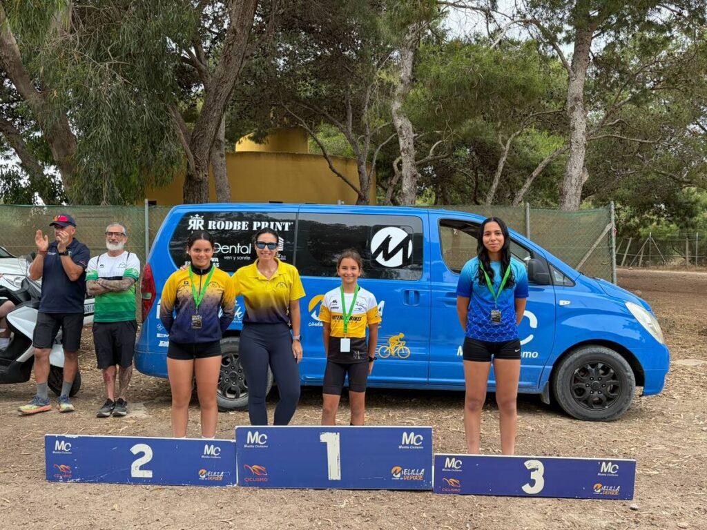 Tres jóvenes ciclistas en el podio tras una competencia de ciclismo
