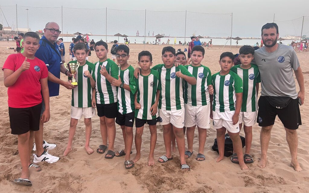 Equipo Milenium F.S. posando con trofeo en la playa