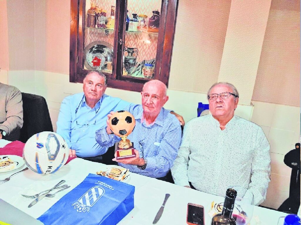 Pedro Botello sosteniendo un trofeo en una reunión con amigos